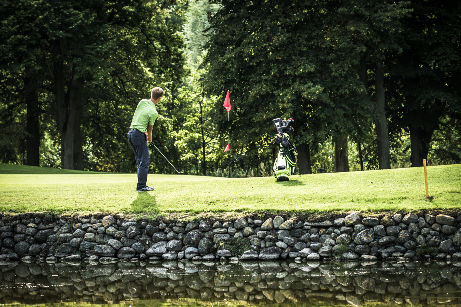 Ein Golfer auf der SCHLOSS Golfanlage mit Teich.