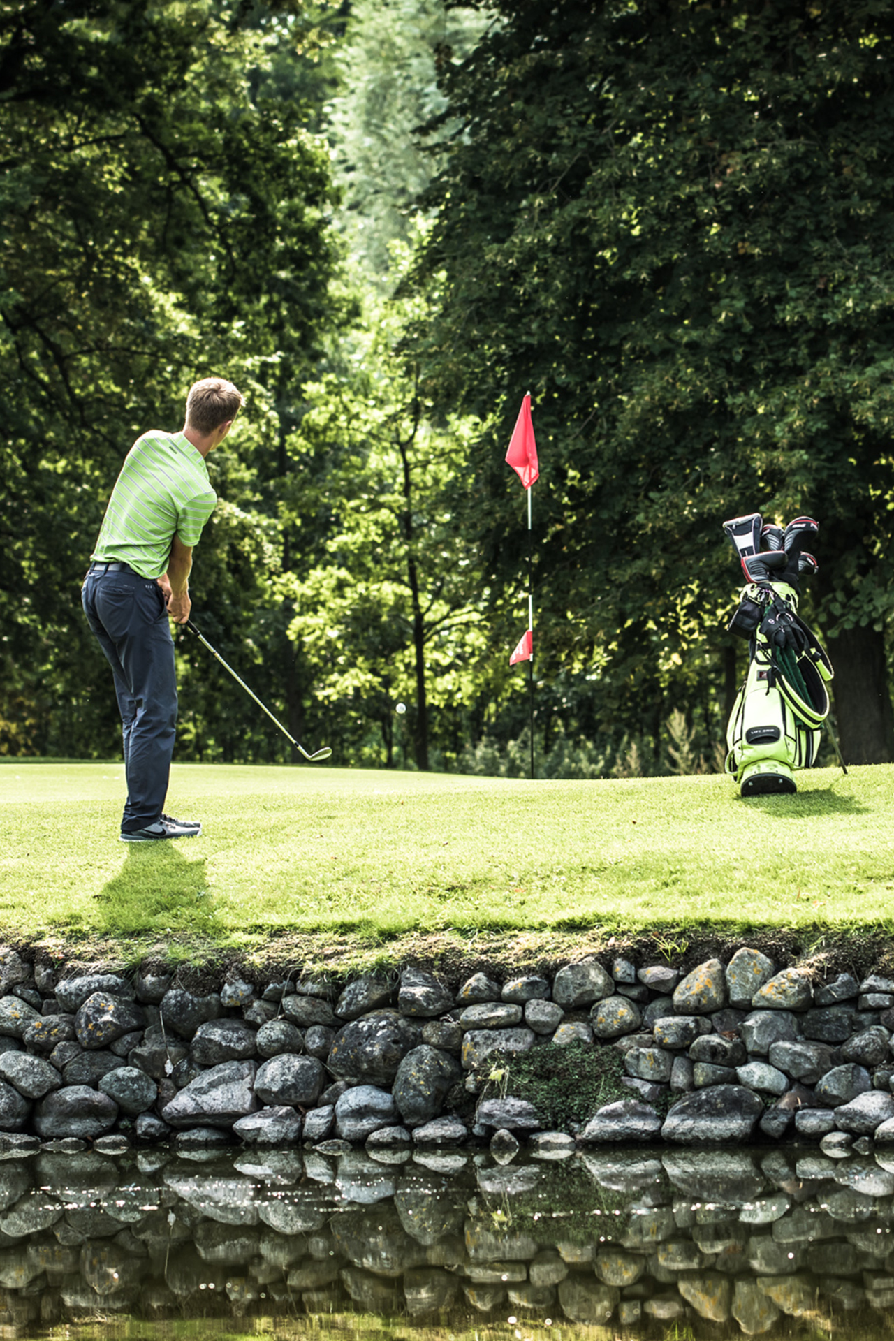 Ein Golfer auf der Golfanlage mit Teich.