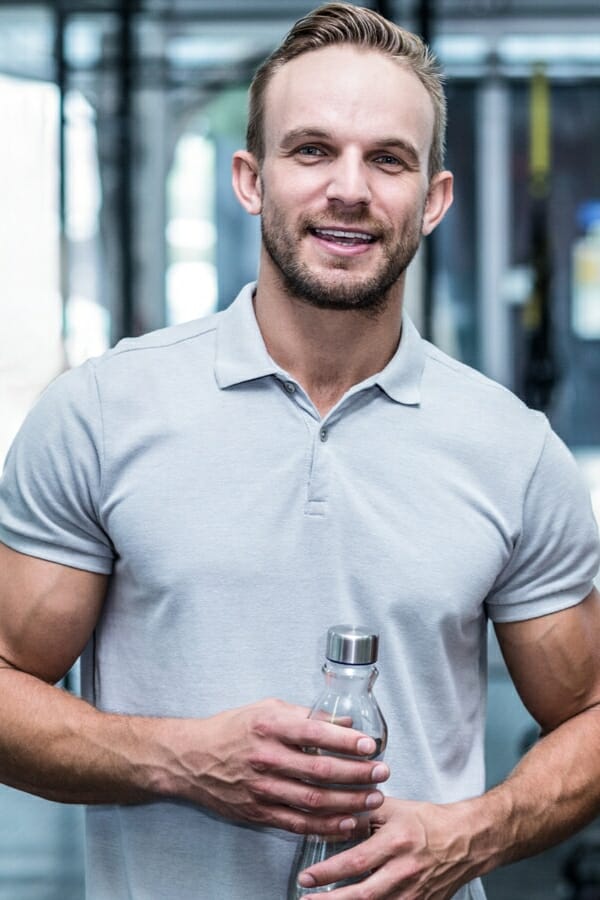 Ein Mann mit einer Flasche im Fitnessstudio.