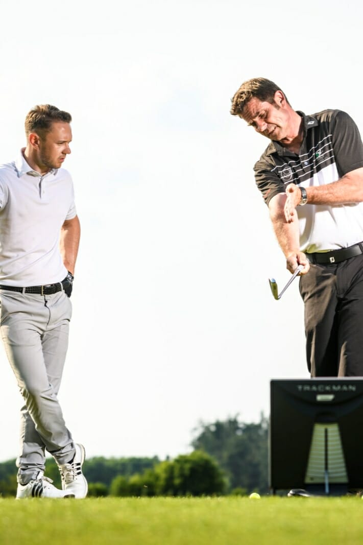 Sven Strüver erklärt einem Mann etwas auf einem Golfplatz.