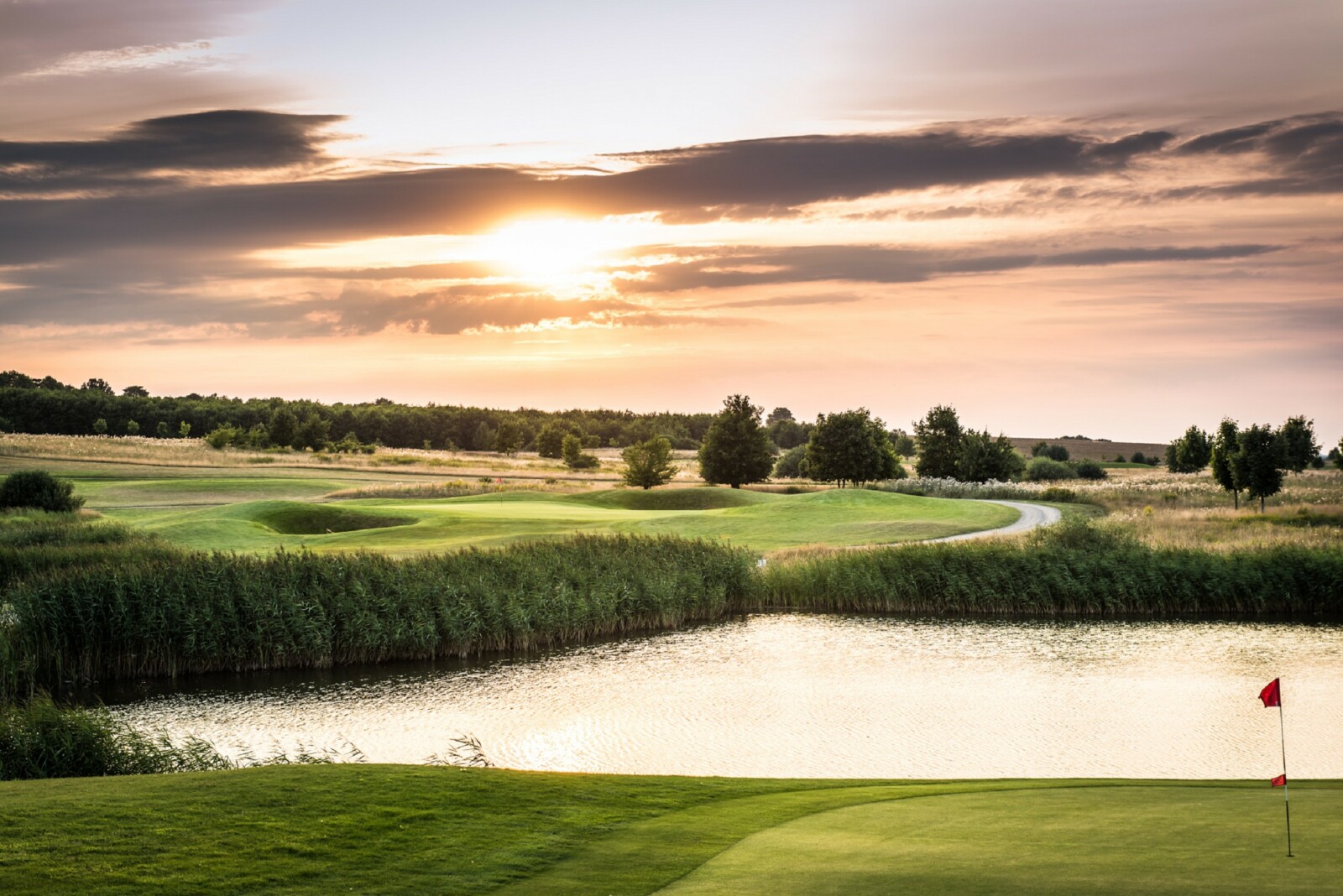 Der Schloss Golfplatz mit Teich im Sonnenuntergang.