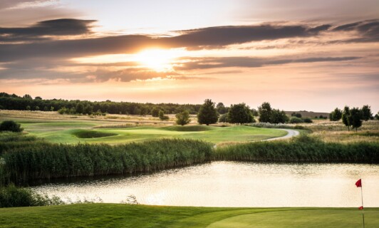 Der Schloss Golfplatz mit Teich im Sonnenuntergang.