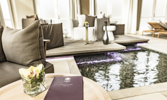 Broschüre mit den Anwendungen des Schloss Spa im Lounge Bereich des Spa auf einem Tisch.