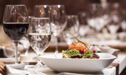 Wein und Wasser neben einem Teller beim Weindinner.