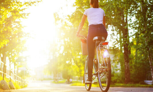Eine Frau fährt Fahrrad im Sonnenschein.