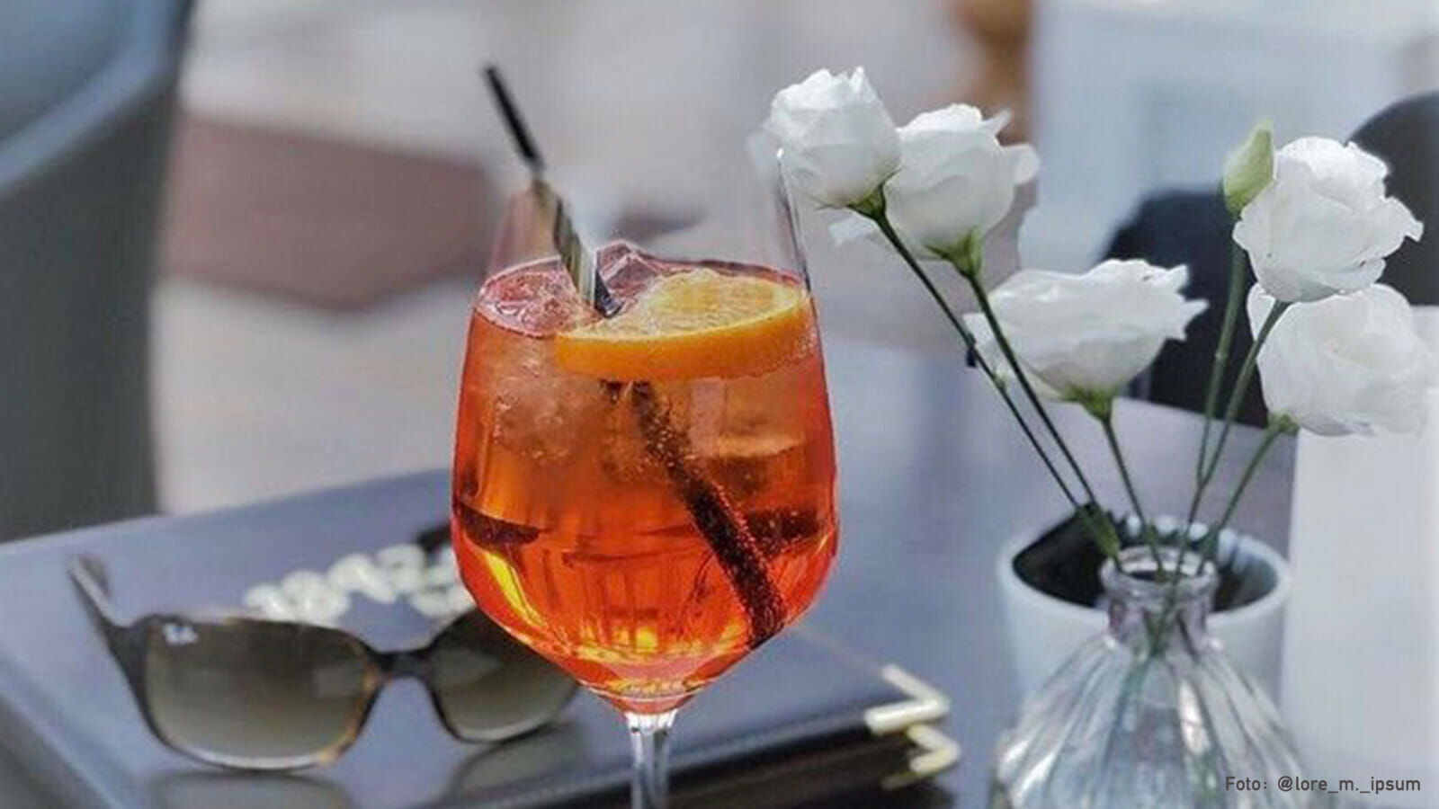 Aperol Spritz auf einem Tisch mit Rosen.