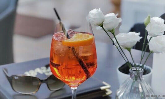 Aperol Spritz auf einem Tisch mit Rosen.