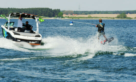 Ein Wakeboarder auf einem See hängt an einem Motorboot.