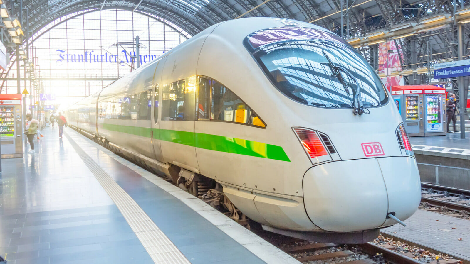 Ein ICE mit grünem Streifen im Bahnhof am Gleis.