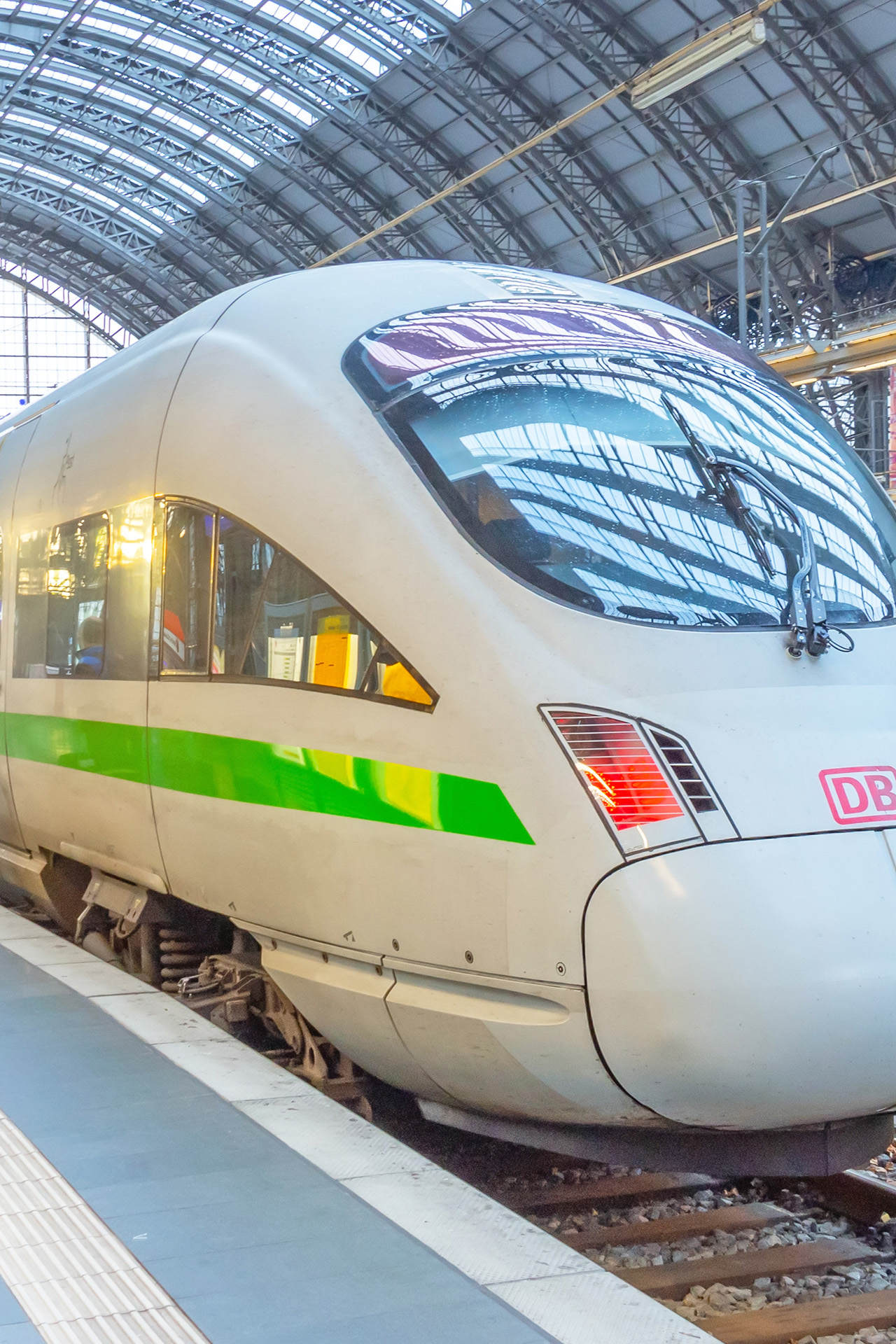 Ein ICE mit grünem Streifen im Bahnhof am Gleis.