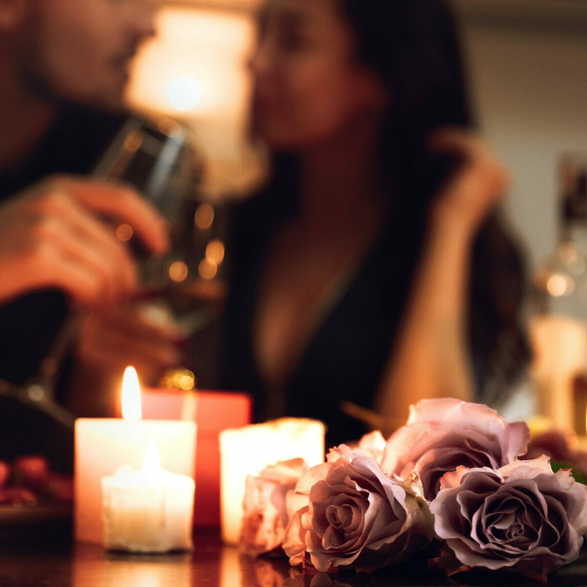 Ein Paar bei einem romantischen Dinner mit Kerzenschein und Rosen.