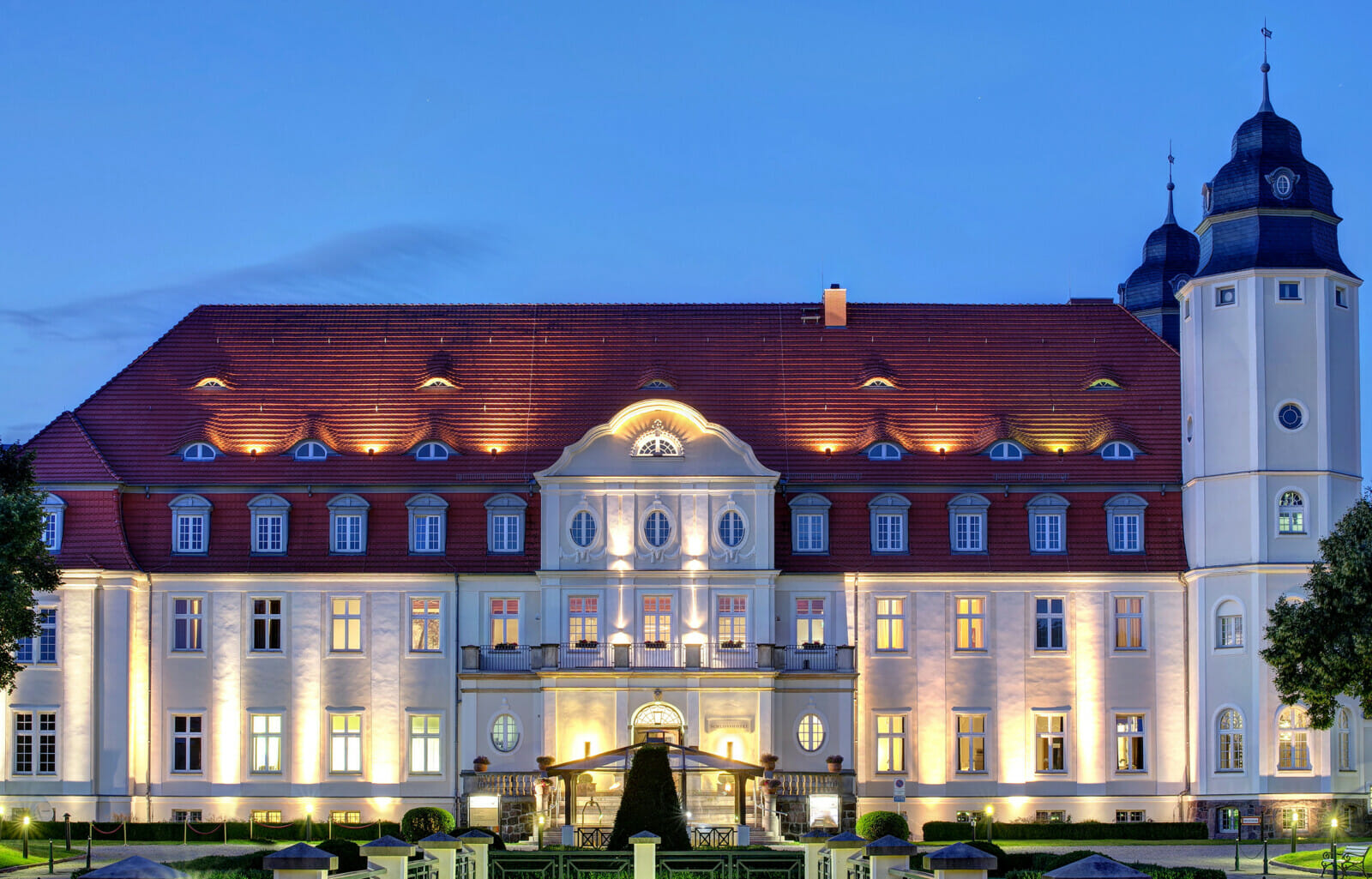 Das beleuchtete Schloss Fleesensee als Tagungshotel Mecklenburg-Vorpommern im Abendlicht.