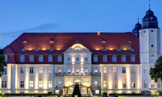 Das beleuchtete Schloss Fleesensee als Tagungshotel Mecklenburg-Vorpommern im Abendlicht.