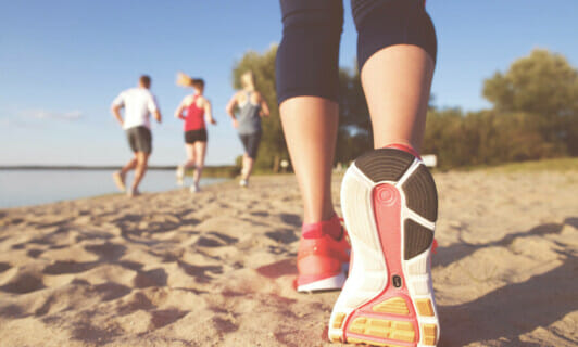 Die Schuhsohle eines Laufschuhs einer Joggerin am Strand.