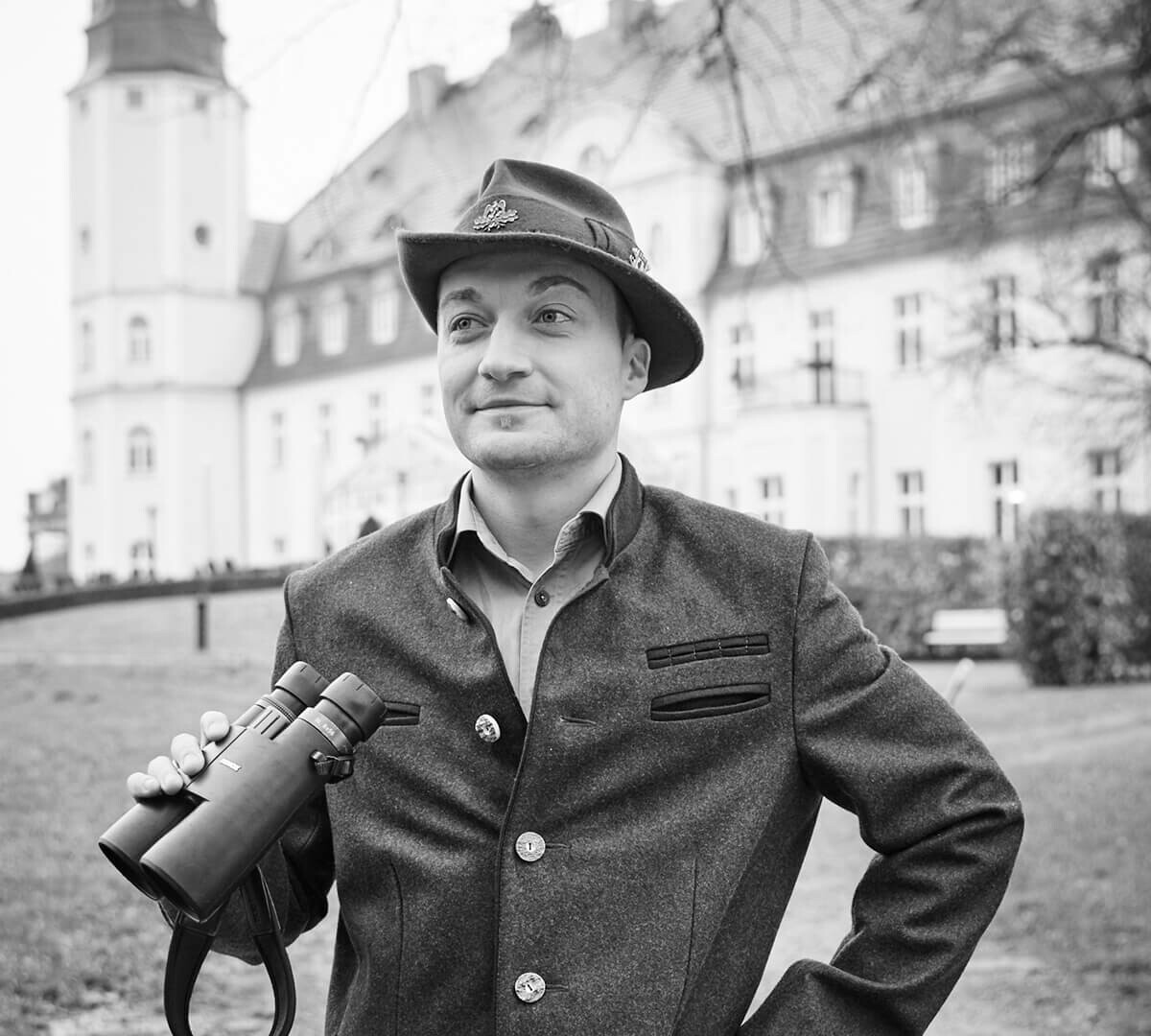 Ein Jäger mit Fernglas steht vor dem Schloss Fleesensee.