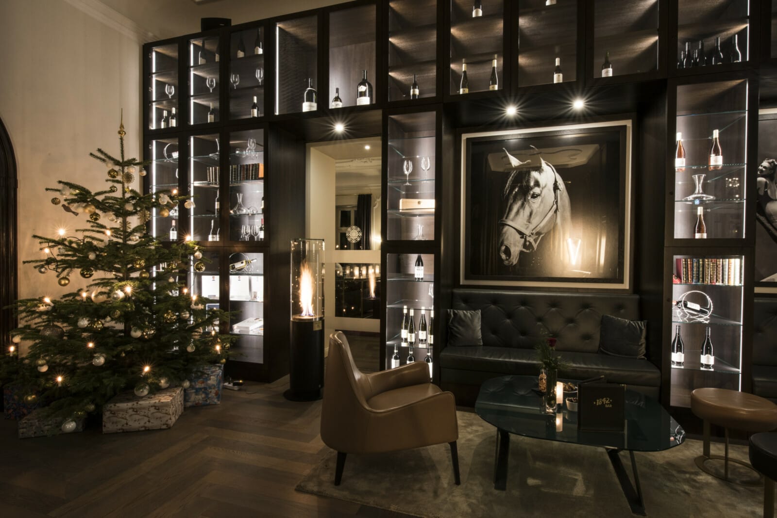 Eine hohe Glasvitrine, davor eine Sitzecke und ein Weihnachtsbaum.