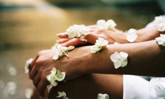 Mit Blüten bedeckte Hände im Zeichen von Ayurveda