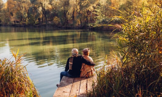 Pärchen sitzend am See bei Herbst am Schlosshotel Fleesensee